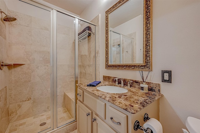 bathroom featuring vanity, a shower with door, and toilet