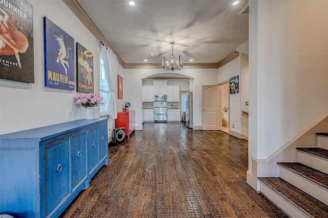 hallway featuring ornamental molding, dark hardwood / wood-style floors, and a notable chandelier