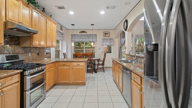 kitchen with light tile patterned flooring, appliances with stainless steel finishes, sink, backsplash, and hanging light fixtures