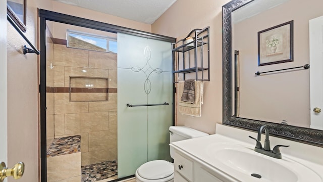 bathroom with toilet, a stall shower, vanity, and a textured ceiling