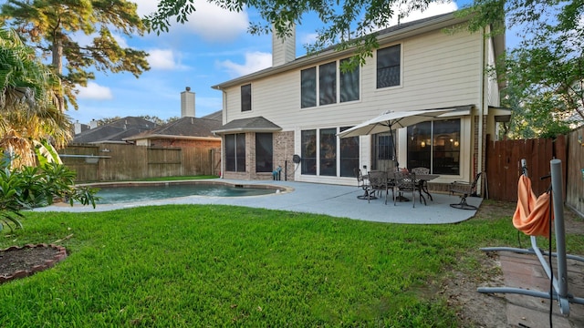 rear view of house with a fenced in pool, a yard, and a patio area