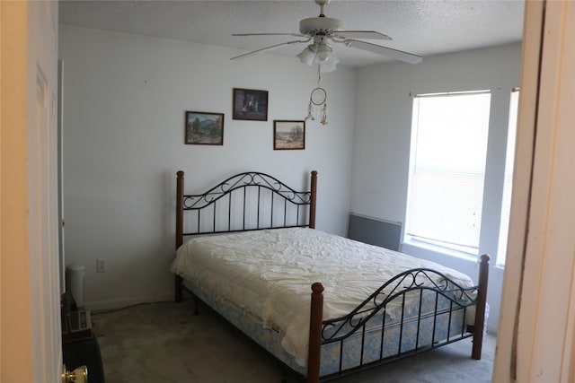 bedroom with multiple windows, a textured ceiling, and dark carpet