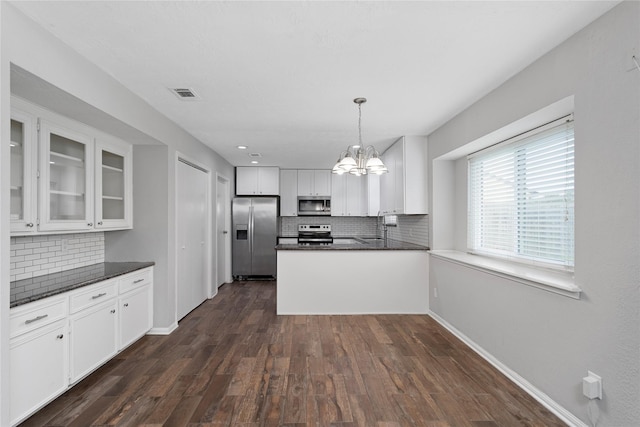 kitchen featuring appliances with stainless steel finishes, white cabinetry, hanging light fixtures, kitchen peninsula, and dark wood-type flooring