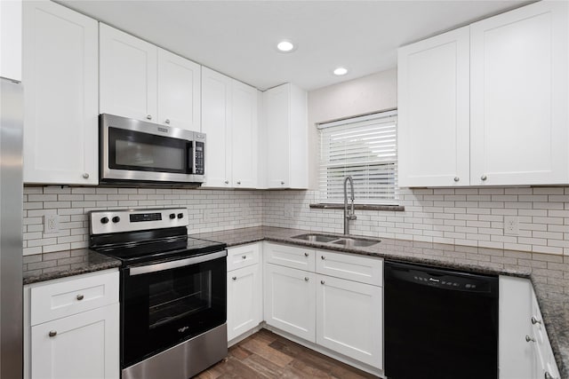 kitchen featuring appliances with stainless steel finishes, white cabinetry, sink, backsplash, and dark stone counters