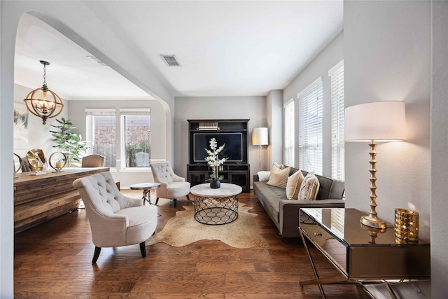 living area with an inviting chandelier, dark hardwood / wood-style floors, and a wealth of natural light