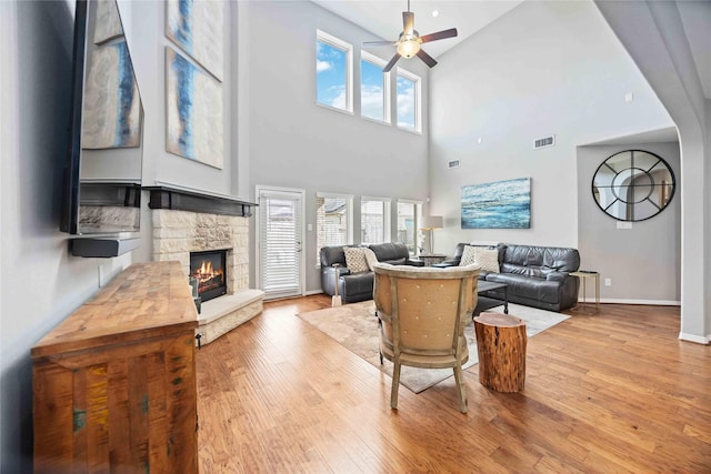 living room featuring a wealth of natural light, a fireplace, ceiling fan, and light wood-type flooring