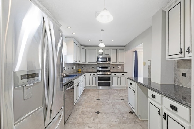 kitchen with dark stone countertops, appliances with stainless steel finishes, backsplash, decorative light fixtures, and gray cabinets