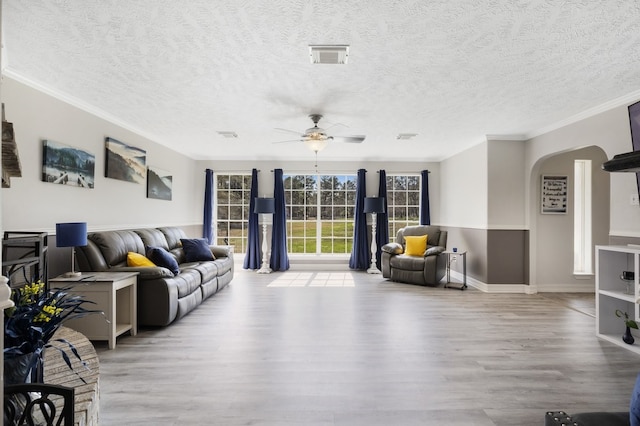 living room with ceiling fan, light hardwood / wood-style floors, crown molding, and a textured ceiling