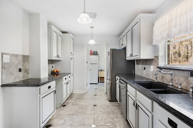 kitchen with white cabinetry, hanging light fixtures, sink, appliances with stainless steel finishes, and decorative backsplash