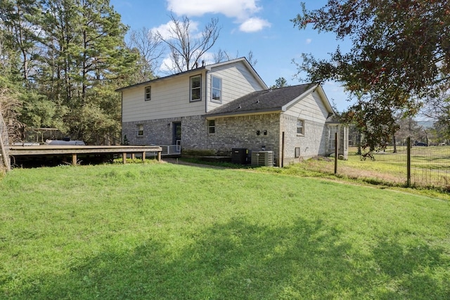 rear view of house featuring central air condition unit and a lawn