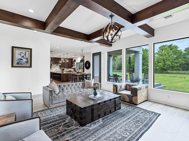 living room with beamed ceiling, an inviting chandelier, and light hardwood / wood-style flooring