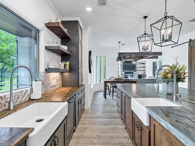 kitchen featuring a barn door, decorative light fixtures, sink, and dark stone countertops