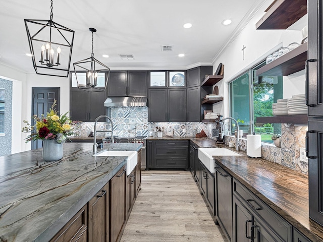 kitchen featuring pendant lighting, sink, dark stone countertops, and dark brown cabinetry