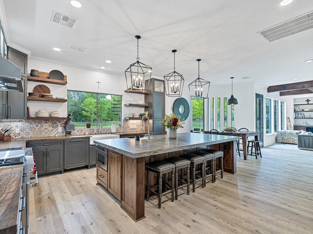 kitchen with appliances with stainless steel finishes, a breakfast bar, pendant lighting, sink, and a spacious island