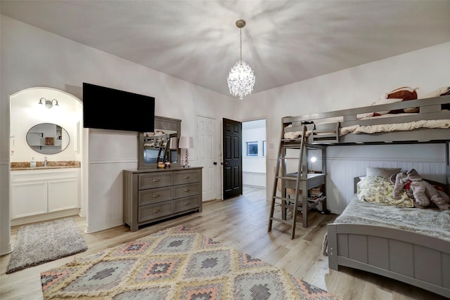 bedroom featuring connected bathroom, a notable chandelier, light hardwood / wood-style floors, and sink