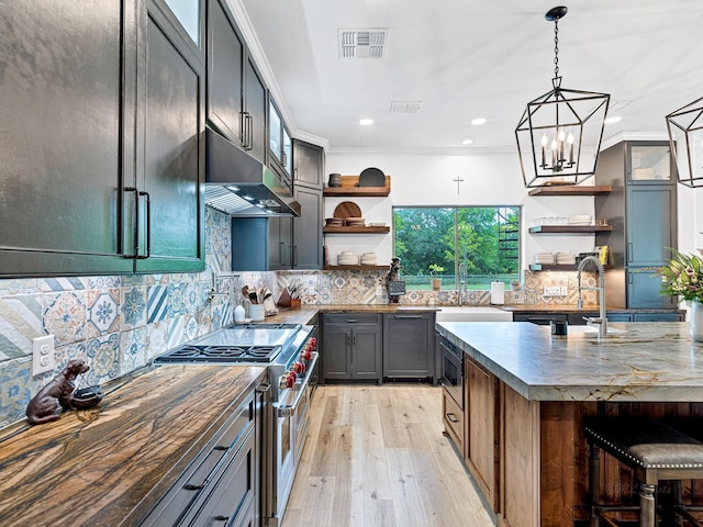 kitchen with sink, backsplash, hanging light fixtures, stainless steel appliances, and light wood-type flooring