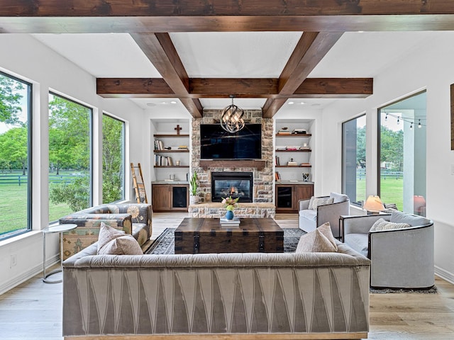 living room featuring beamed ceiling, a large fireplace, built in features, and light wood-type flooring