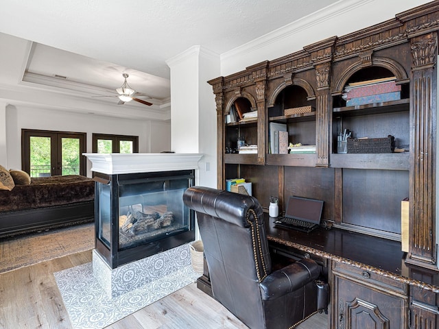 office space with crown molding, ceiling fan, a multi sided fireplace, french doors, and light wood-type flooring