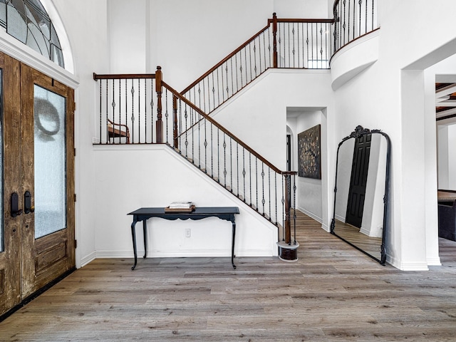 foyer entrance with light hardwood / wood-style flooring, french doors, and a high ceiling