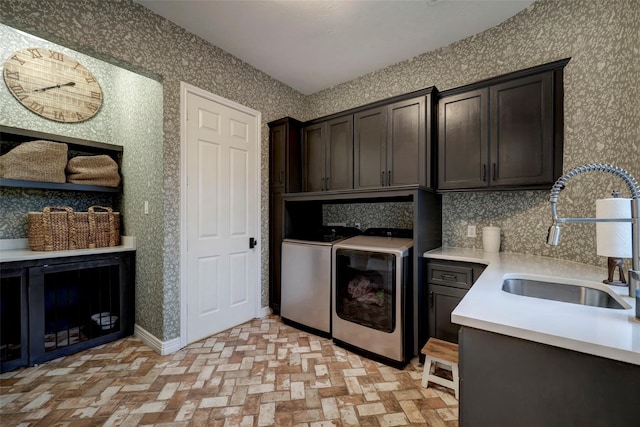 clothes washing area with cabinets, washer and dryer, and sink