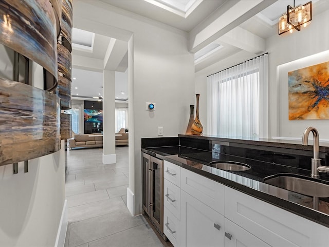 kitchen featuring white cabinetry, hanging light fixtures, dark stone countertops, light tile patterned flooring, and beverage cooler