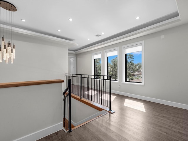 interior space with a tray ceiling and wood-type flooring