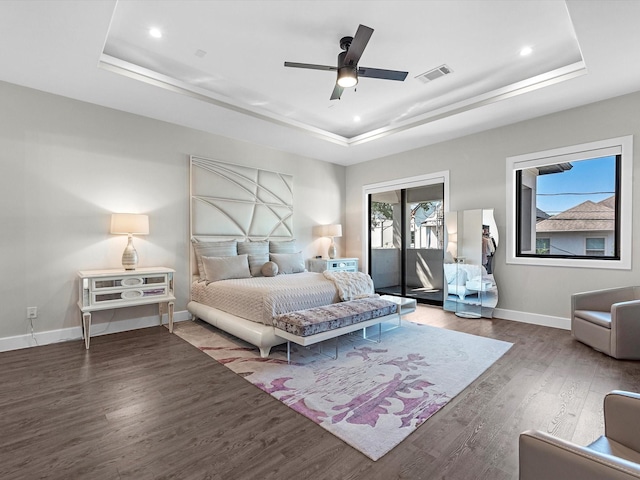 bedroom with dark hardwood / wood-style flooring, a raised ceiling, and ceiling fan