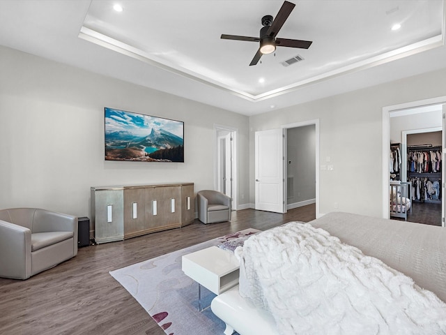 bedroom featuring dark hardwood / wood-style flooring, a raised ceiling, and ceiling fan