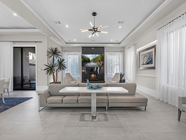 living room with ornamental molding, light tile patterned floors, a notable chandelier, and a tray ceiling