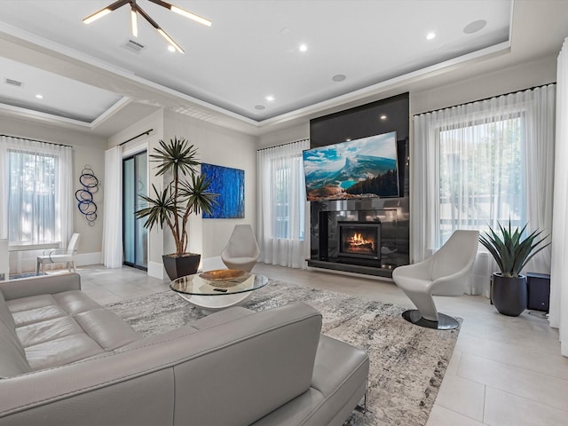 tiled living room with crown molding, a fireplace, and a raised ceiling