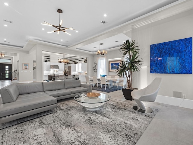 living room featuring ornamental molding, a healthy amount of sunlight, a tray ceiling, and a chandelier