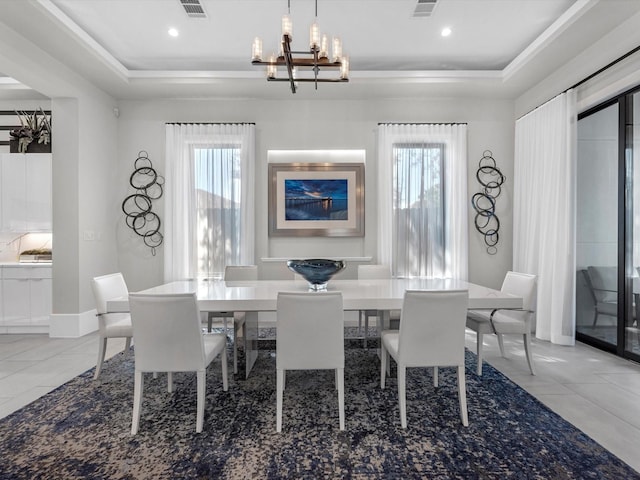 dining room with an inviting chandelier, a tray ceiling, and tile patterned flooring