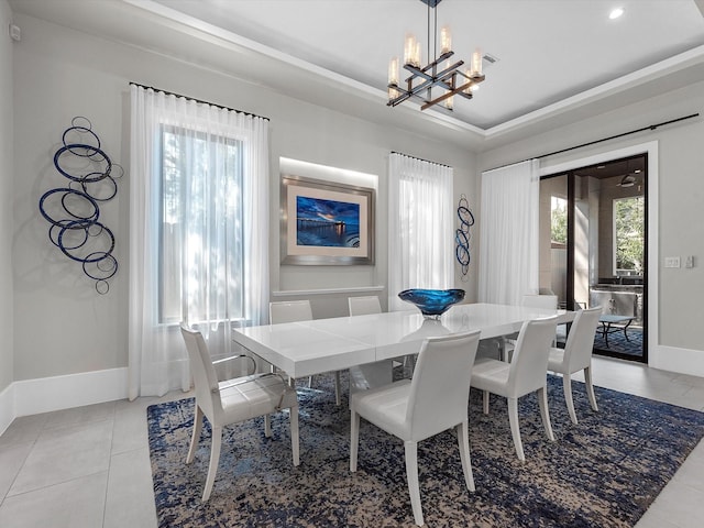 tiled dining room featuring a raised ceiling and a chandelier