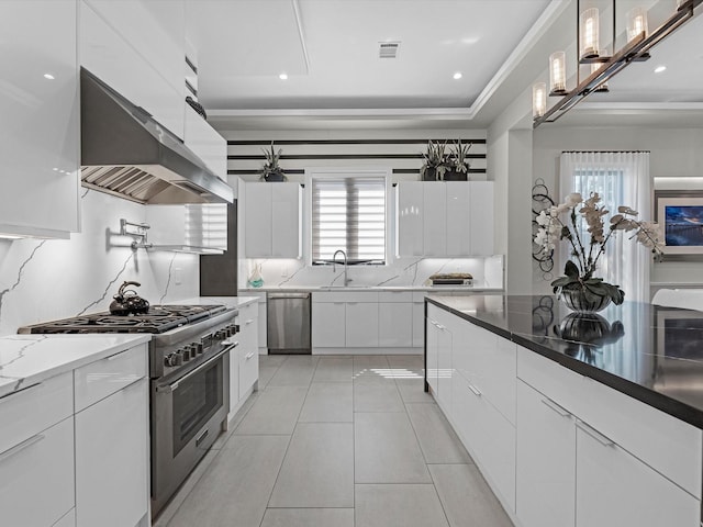 kitchen featuring range hood, hanging light fixtures, stainless steel appliances, and white cabinets