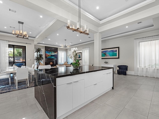 kitchen with a raised ceiling, white cabinetry, pendant lighting, and a spacious island