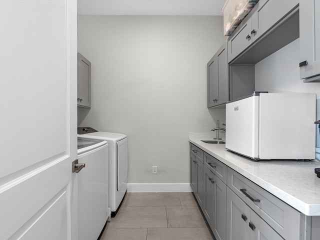 washroom with sink, light tile patterned floors, washer and clothes dryer, and cabinets