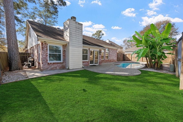 back of house featuring a fenced in pool, a yard, and a patio area