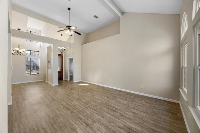 unfurnished living room with hardwood / wood-style flooring, ceiling fan with notable chandelier, high vaulted ceiling, and beamed ceiling