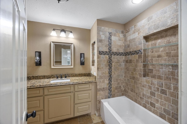 bathroom with vanity, a textured ceiling, and tiled shower / bath