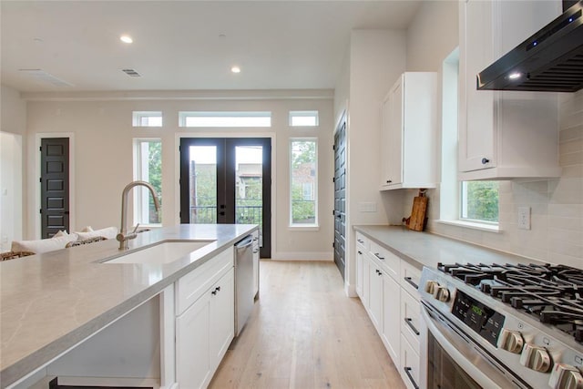 kitchen featuring sink, white cabinets, backsplash, stainless steel appliances, and wall chimney exhaust hood