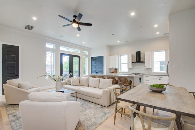 living room featuring french doors, ceiling fan, and light wood-type flooring