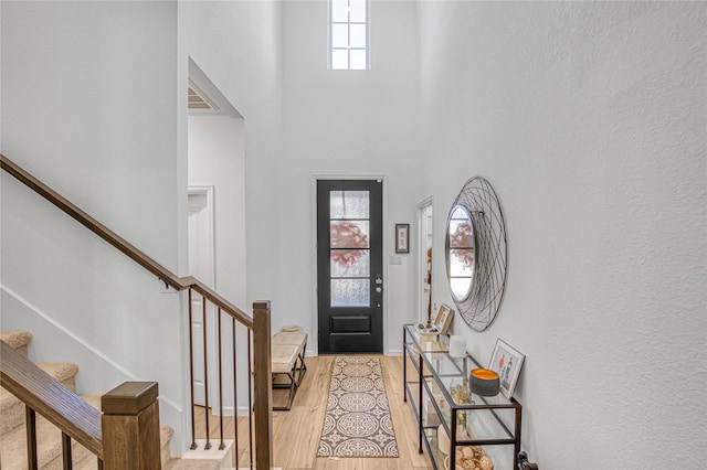 entryway featuring a towering ceiling and light wood-type flooring