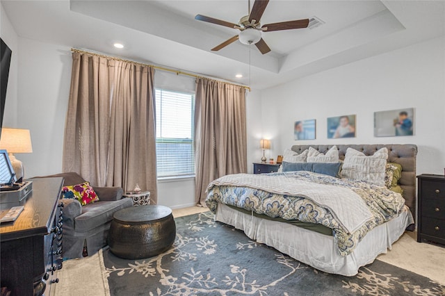 carpeted bedroom featuring ceiling fan and a tray ceiling