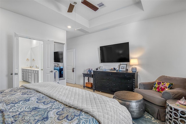 bedroom featuring a raised ceiling, ceiling fan, sink, and ensuite bath