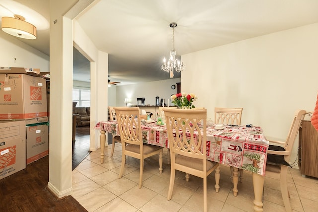 tiled dining room with ceiling fan with notable chandelier