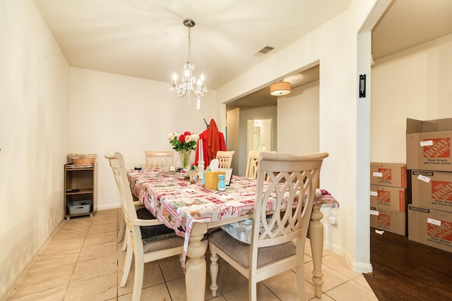 dining area with light tile patterned floors and an inviting chandelier