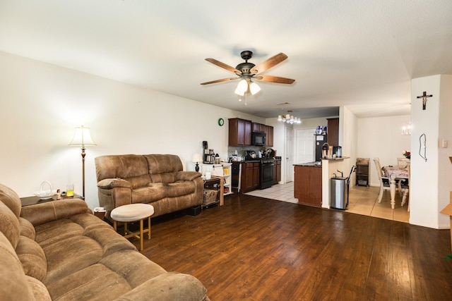 living room featuring ceiling fan with notable chandelier and light hardwood / wood-style flooring