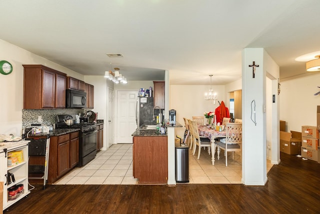 kitchen featuring pendant lighting, decorative backsplash, light hardwood / wood-style floors, black appliances, and an inviting chandelier