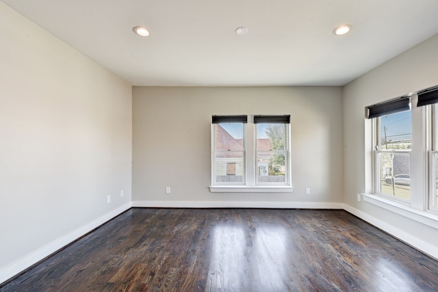 spare room with plenty of natural light and dark hardwood / wood-style flooring