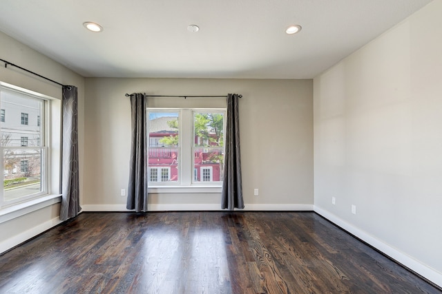 empty room with dark hardwood / wood-style flooring and a wealth of natural light